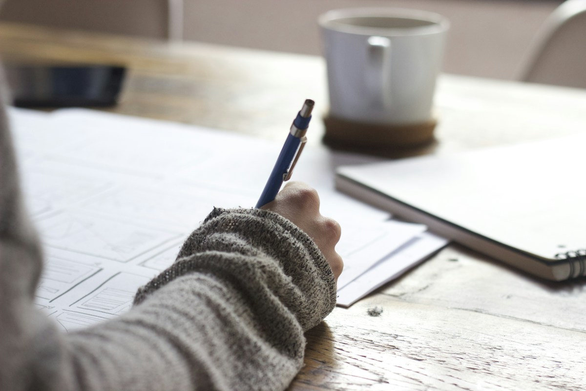 A learner taking notes at a bright desk